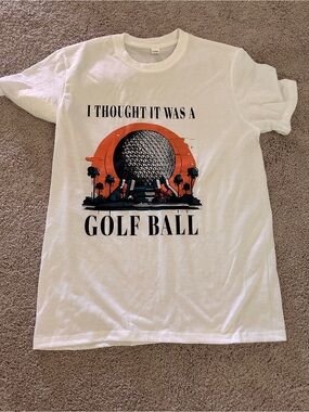 Graphic Tee — 'I Thought It Was A Golf Ball' in White with Orange & Black Print